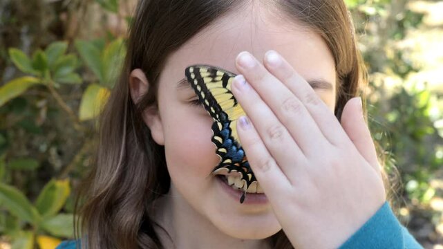 Little girl smiling with colorful butterfly on her face.