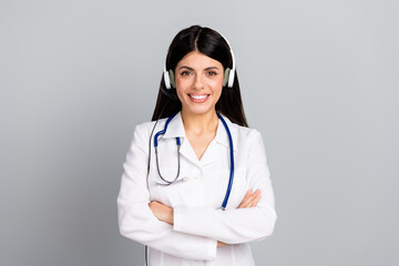 Fototapeta premium Young female doctor smiling confidently while wearing headset and white medical uniform on a grey background