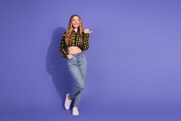 Young woman in trendy outfit posing confidently against vibrant purple background