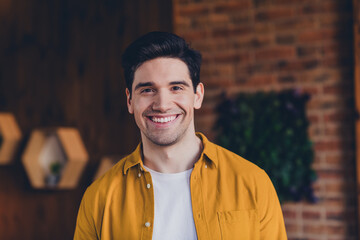 Young man smiling indoors in a cozy loft with stylish design and natural daylight