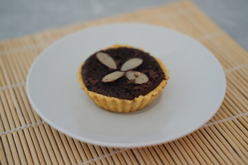 Chocolate tart with almond on white plate. Selective focus.