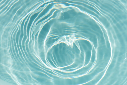 Blue water with ripples on the surface. Defocus blurred transparent blue colored clear calm water surface texture with splashes and bubbles. Water waves with shining pattern texture background.
