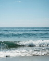 A serene beach scene with gentle waves and a clear blue sky.
