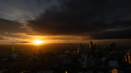 Fototapeta premium A breathtaking sunset casts a golden glow over the Manchester skyline, highlighting the majestic architecture and urban landscape in the evening light.