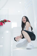 Joyful Young Woman Sitting on White Stairs in Bright Space
