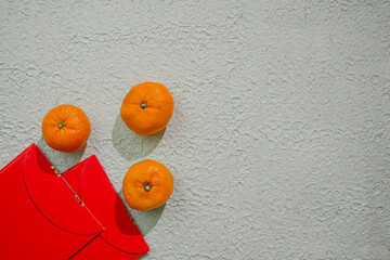 Red angpao and tangerine or mandarin oranges isolated on a white background, symbolizing...