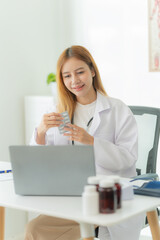 Asian female doctor working with laptop Convenient online consultation for patients Sitting at the clinic table Provide online health consultation vertical picture