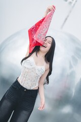 Joyful Young Woman Holding Red Bandana with Silver Background