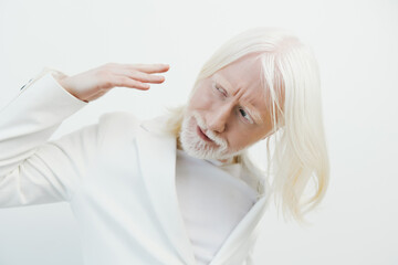 Portrait of an elderly man with long white hair and a beard, wearing a stylish white suit against a minimalistic white background, embodying elegance and sophistication