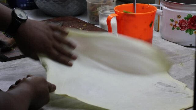 The process of making or cooking an Martabak Telur. Frying with hot oil in a pan, snacks are made from flour filled with eggs, meat, vegetables, and spices.
