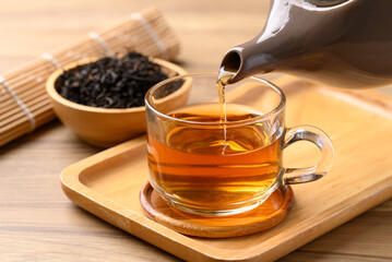 Black tea in cup glass with teapot pouring tea, Healthy herbal drink