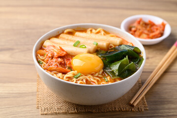 Spicy noodles soup with Tteokbokki, Wakame seaweed and fresh egg yok eating with kimchi cabbage