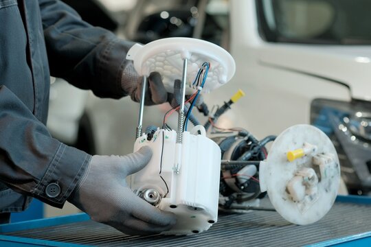 The fuel module. Close-up. An auto mechanic is preparing a new fuel module for installation. There is a faulty fuel module on the desktop nearby.