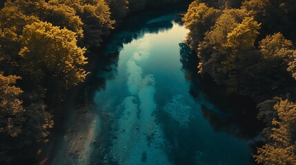 Obraz premium Aerial view of turquoise river flowing through lush green forest at sunset