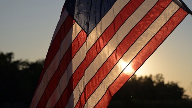 American Flag Waves at Sunset in Nature Symbolizing Freedom and Unity Vibrant Colors Against a Serene Backdrop Inspiring Viewpoint