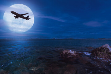 An Airplane Gliding Smoothly Under a Radiant Full Moon That Is Located Above Calm Water