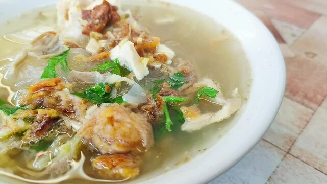 Healthy and delicious traditional Indonesian chicken soup made with chicken, ginger and spices on bokeh background