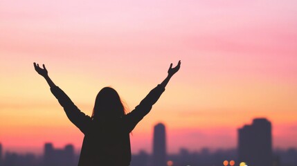 Fototapeta premium A woman stands with her arms raised high, celebrating her achievement as a colorful dusk sky blankets the city, filling the scene with joy