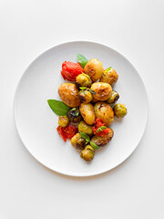 Overhead view of plate with roasted baby potatoes, Brussels sprouts, and cherry tomatoes garnished with fresh basil, clean eating concept with copy space.