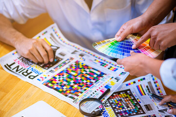 Team graphic designer checking print quality of media graphics proof print and color guides in...