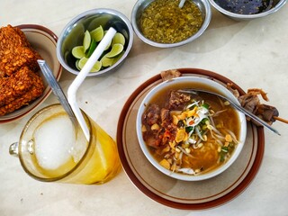 Soto Kudus, a traditional Indonesian chicken soup, served with side dishes. Indonesian cuisine.
