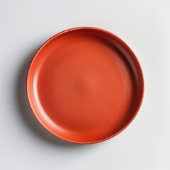 A simple, round, orange plate displayed against a neutral background, emphasizing its smooth texture and vibrant color.