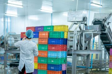 Obraz premium A factory worker wearing protective gear, organizing colorful storage crates in a clean and modern industrial facility, showcasing efficiency, cleanliness, and organization in industrial operations.