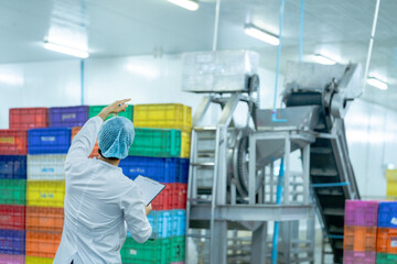 A factory worker wearing protective gear, organizing colorful storage crates in a clean and modern industrial facility, showcasing efficiency, cleanliness, and organization in industrial operations.