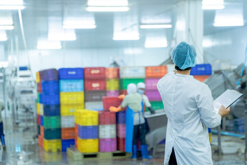 A factory worker wearing protective gear, organizing colorful storage crates in a clean and modern industrial facility, showcasing efficiency, cleanliness, and organization in industrial operations.