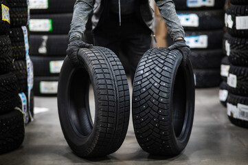 Mechanic keeps new summer and winter car tires in the garage. Comparison of wheels for different seasons. 