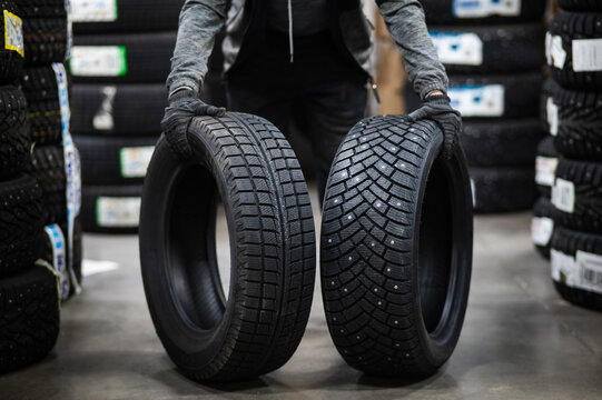 Mechanic keeps new summer and winter car tires in the garage. Comparison of wheels for different seasons. 