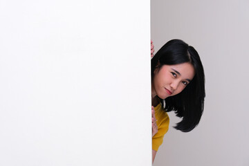 A woman peeking out behind a wall with suspicious expression