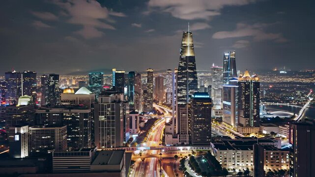 Aerial Drone view of a bustling city landscape at night with gray clouds and black sky horizon background
