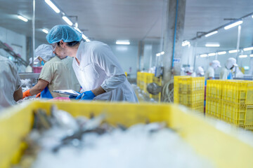 A supervisor in a food processing plant wearing protective gear, inspecting a fish while holding a clipboard, emphasizing quality control, hygiene, and safety in the seafood production process.