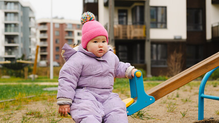 Child Enjoys Playful Swing Time in a Colorful Park on a Chilly Day Surrounded by Modern Buildings