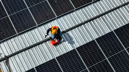 A worker wearing safety gear installing solar panels on a rooftop with nearby housing units in the background, emphasizing renewable energy, sustainability, and efficient solar power implementation