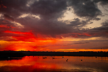 A stunning and breathtaking sunset casts its colors over calm water, creating beautiful reflections