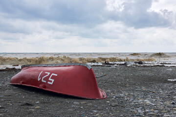 An overturned boat on the seashore after a storm.