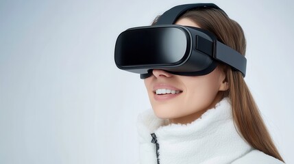 Naklejka premium Smiling woman wearing a black virtual reality headset, immersed in a VR experience against a plain background.