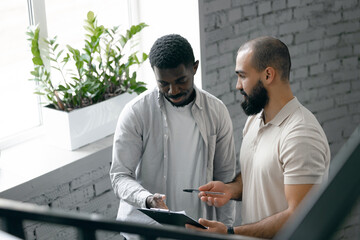 colleagues engaged in discussion, analyzing documents in modern office setting. collaboration,...