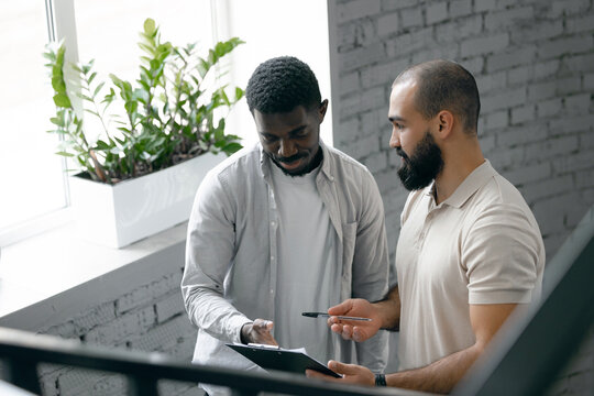 colleagues engaged in discussion, analyzing documents in modern office setting. collaboration, teamwork, and diverse professional environment highlighted in workplace scene