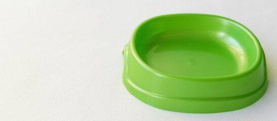 Green plastic bowl for dogs and cats on a white background. Pet supplies. Feeding pets. Background, a place for the text. A bowl for dry food. Allergy to dog food.