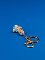 close up of a small snake keychain made of multi-colored rhinestones on a blue background