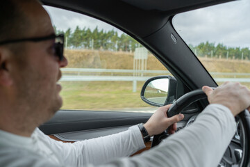 man driving a car with his hands on the steering wheel. High quality photo