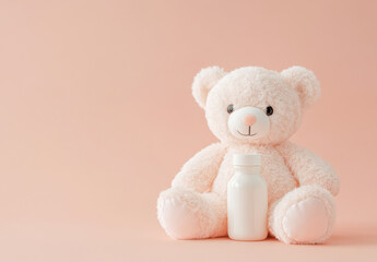 A fluffy teddy bear sits calmly next to a small white bottle on a smooth pastel pink background. This inviting setup creates a warm and friendly atmosphere, perfect for children.