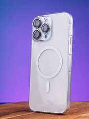 Detailed view of a smartphone with three cameras, housed in a sturdy case, set against a purple backdrop.