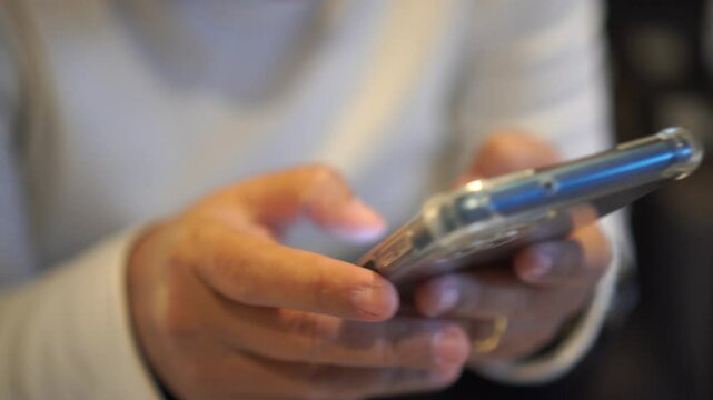 Hands holding smartphone pressing fingerers, reading social media internet, typing shopping online at home