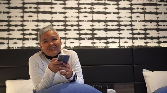 Senior smart chatting in Video call to family in New normal life in bedroom, Reading social media internet and typing text or shopping online with smartphone mobile.