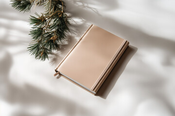 Notebook in soft pastel setting, surrounded by delicate shadows and pine branches, offers a serene atmosphere perfect for reflection or writing moments