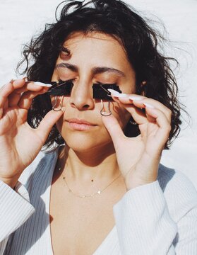 Portrait of young woman with paper clips closing eyes in white bright background